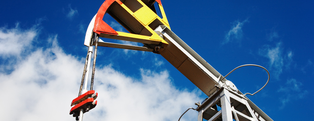 Oil pump jack against blue sky background