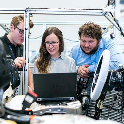 People working on a computer attached to car