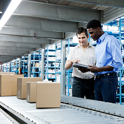 Two men in front of conveyor belt of boxes