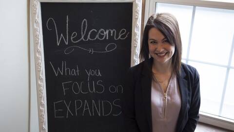 image of nicole standing next to a chalkboard that says welcome