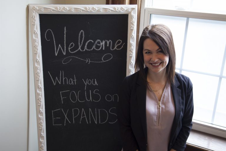 image of nicole standing next to a chalkboard that says welcome
