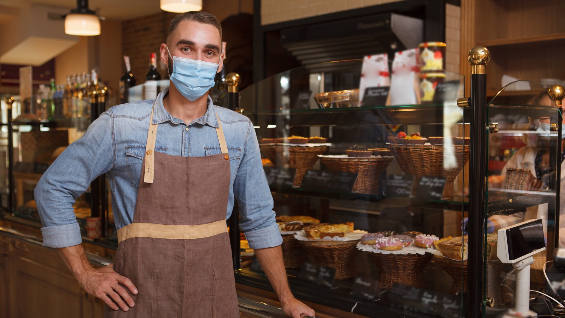 Male baker wearing medical face mask working at his bakery store during coronavirus quarantine