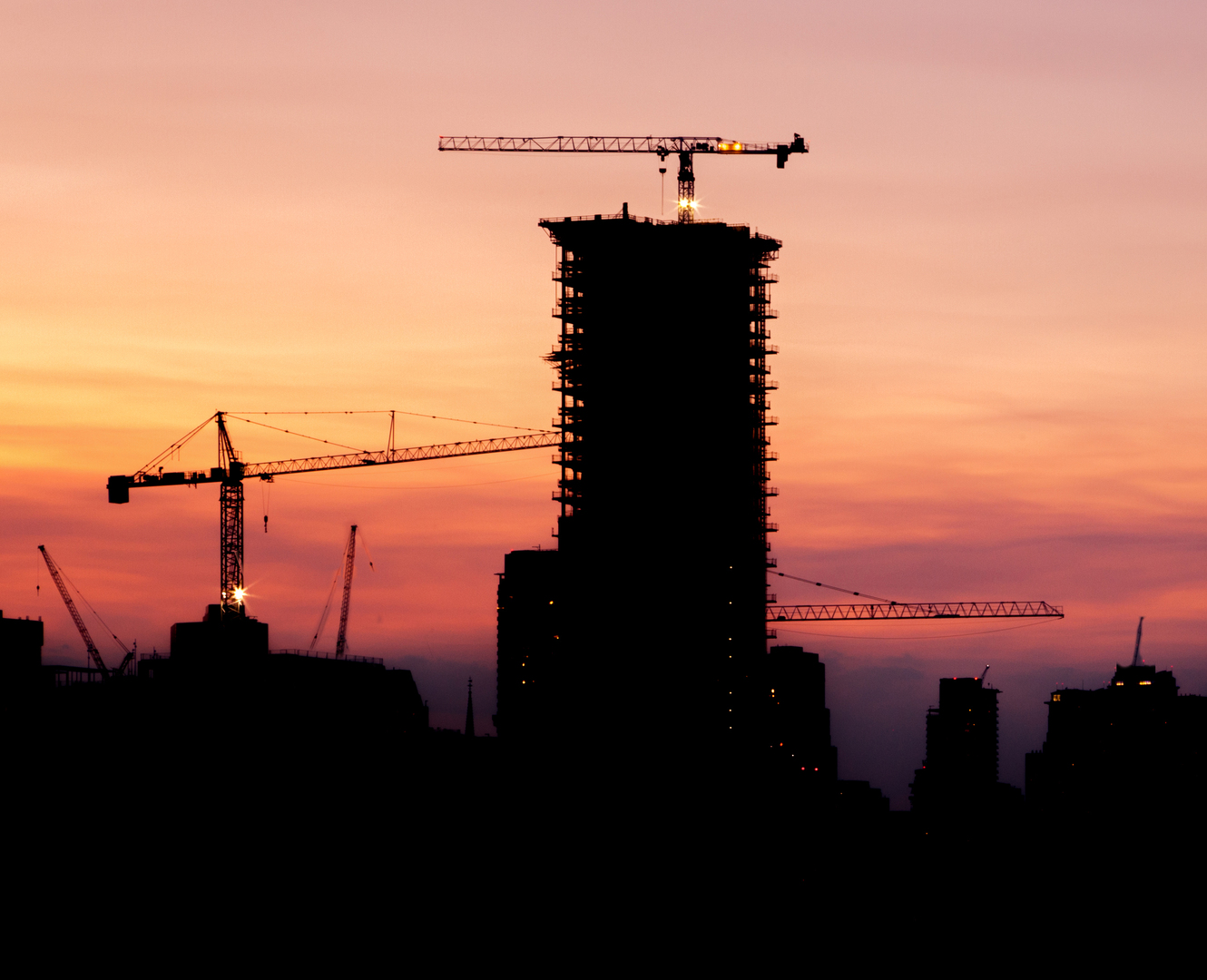 Sunset with cranes and a building under construction