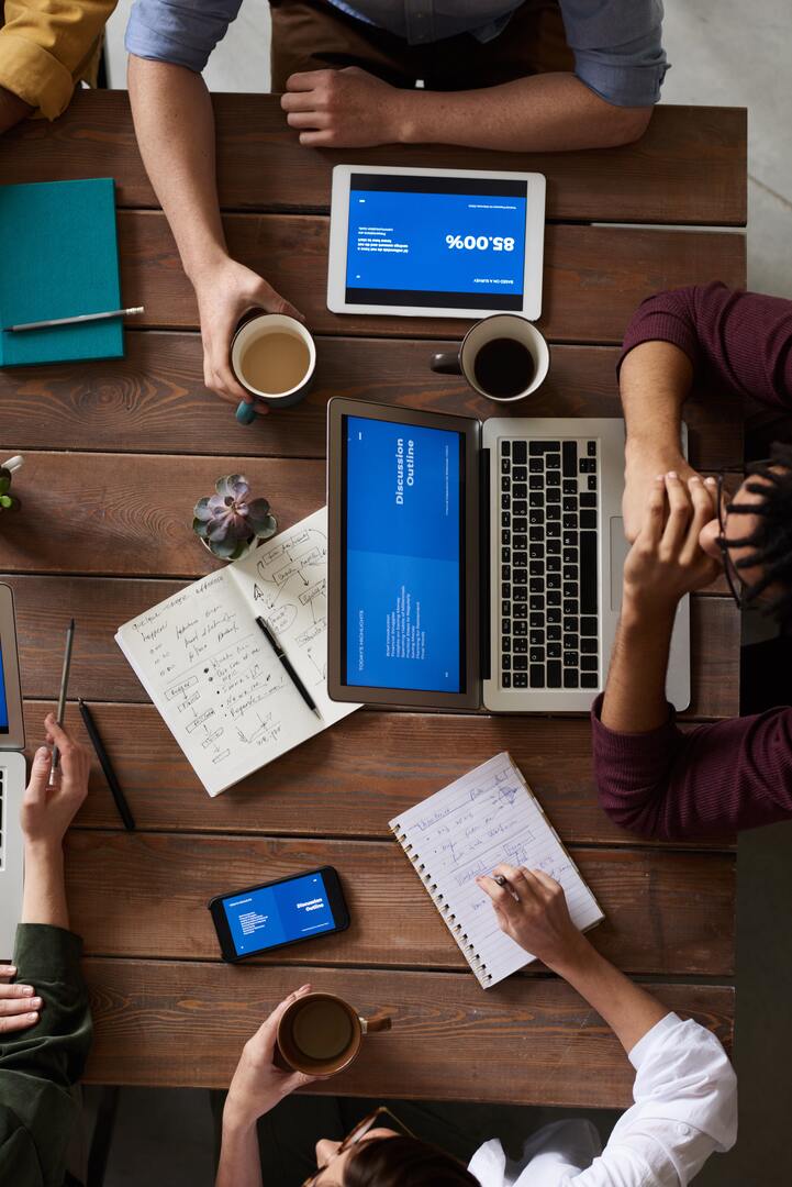 people having a meeting around a table with laptops and coffee mugs