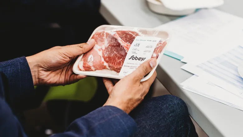 Someone holding meat in packaging