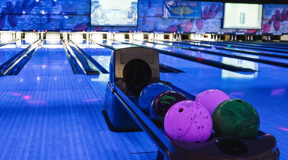 Bowling ball return system holding multiple multi-coloured bowling balls with cosmic blue lighting