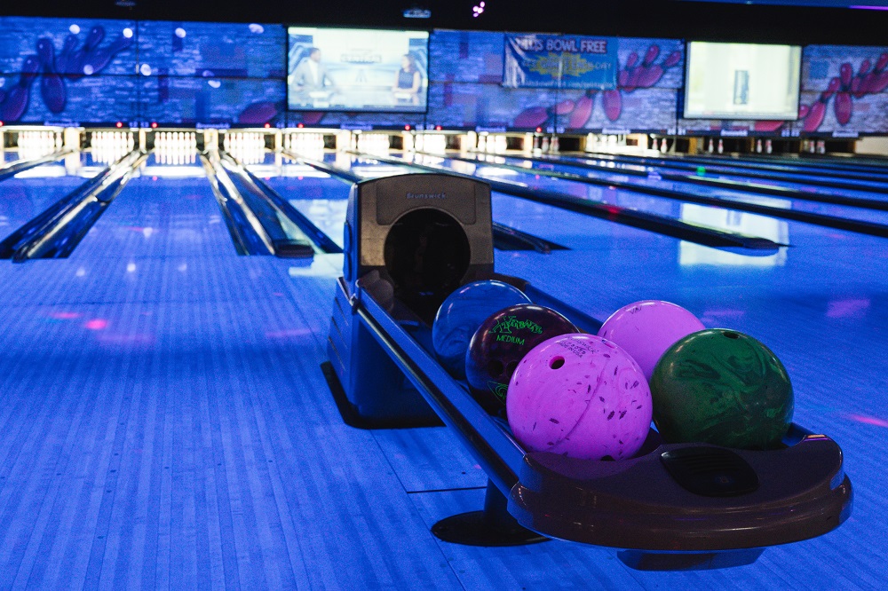Bowling ball return system holding multiple multi-coloured bowling balls with cosmic blue lighting