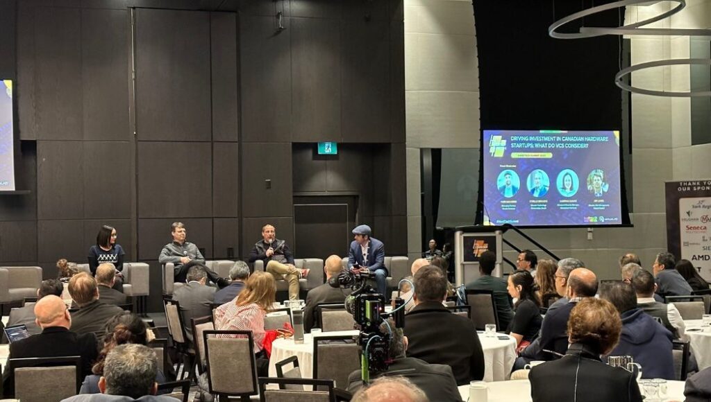 Panelist on stage at VentureLab's Hard Tech conference with attendees sitting at round tables