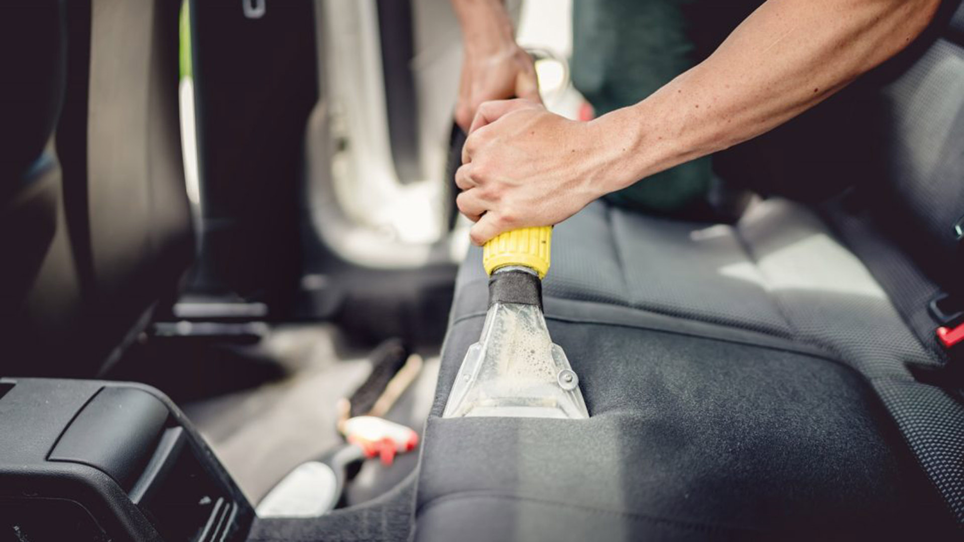 Professional using steam vacuum for draining stains to detail car